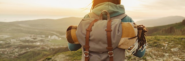 Woman with hiking backpack at the top of a mountain