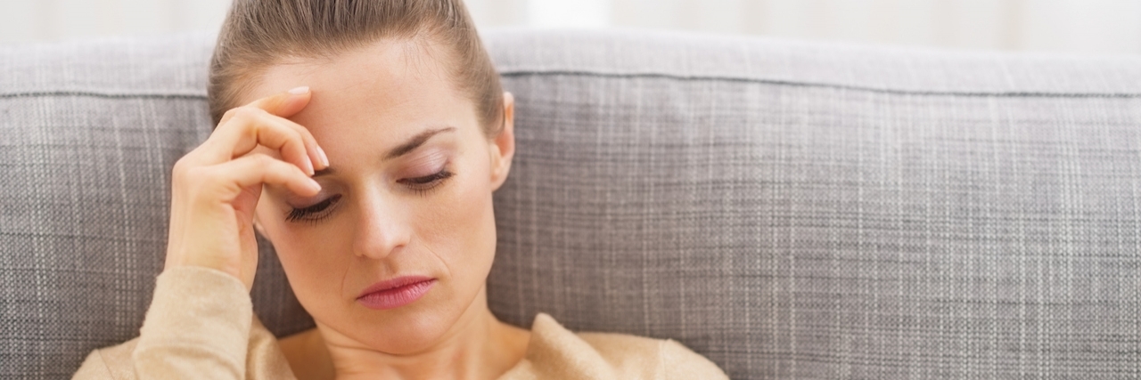 What to Know About Your Loved One Dealing With Depression and Anxiety Stressed woman sits on couch with hand on head