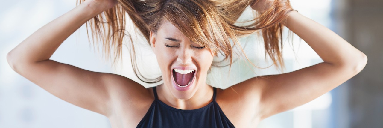 Trichotillomania: Why You Should Stop Saying 'Pull My Hair Out' Woman pulling on her hair and screaming