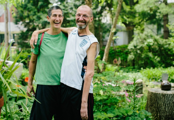 Ray and Rae stand in the garden outside their home. “Early on, we promised to laugh every day,” says Rae. Ray says he's “smiling every day. Crookedly but smiling, nonetheless.”