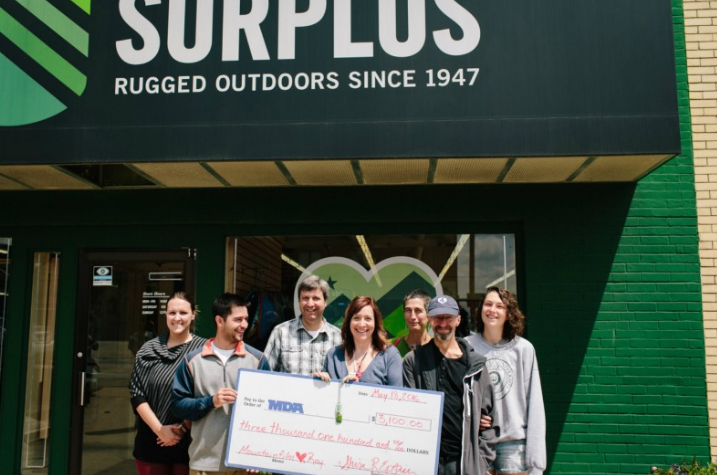 The Spooners pose in front of Champaign Surplus with a check for MDA. “When Rae and I sat down to discuss a goal for our MDA fund raiser, we thought $10,000 sounded an attainable amount. Last week we achieved more than we ever thought imaginable, $80,000.”