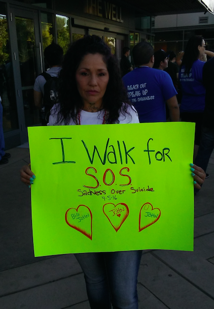 Sharon holds a sigh that reads: I walk for SOS. Sadness Over Suicide