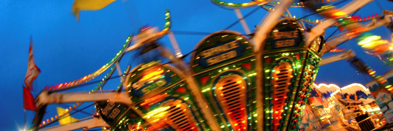 Carnival ride spinning, blurring lights and flags in the night.
