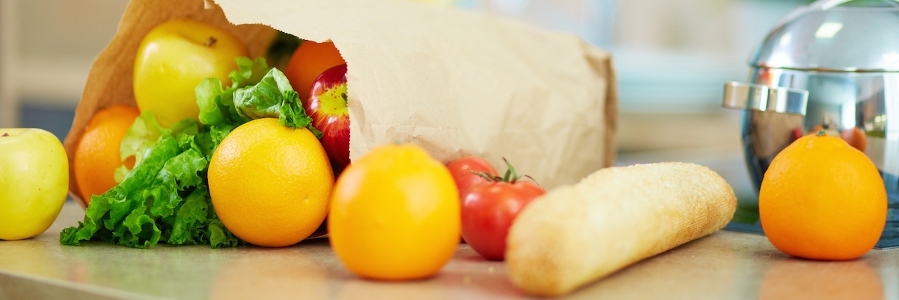 What Not to Say to Family With Dietary Restrictions Close-up of paperbag full of fruits and vegs with female on background