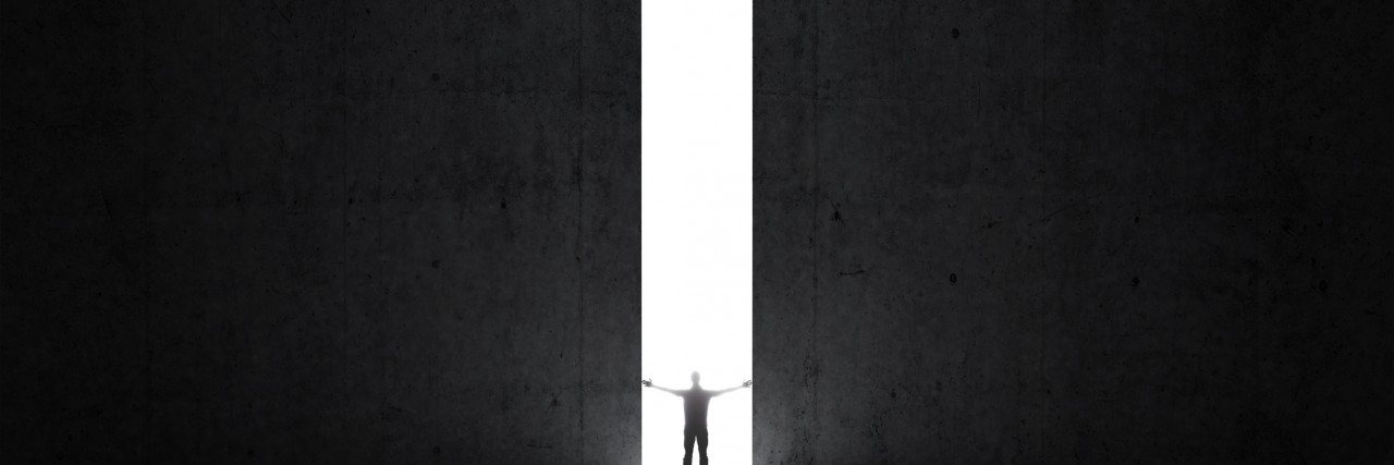 Surviving 5 Suicide Attempts in a Year of Darkness and Depression Dark abstract concrete interior. Man stands in the light of opening.