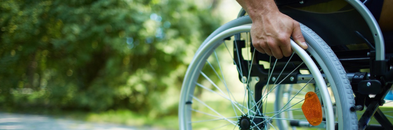 A close-up of a hand pushing a wheelchair.