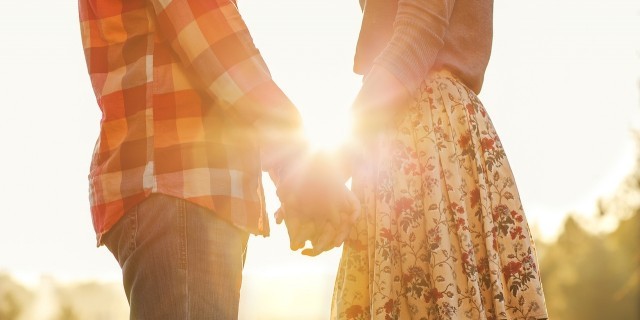 Young couple in love walking in the autumn park holding hands looking in the sunset