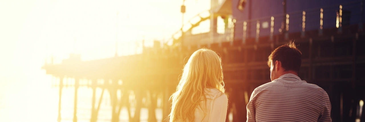 What to Know About Dating Someone With Anxiety Couple sitting together by the beach with sunset