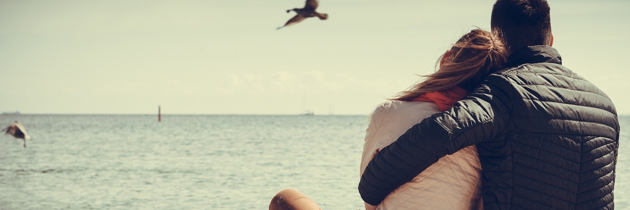 When My Partner Told Me He Forgot About My Depression A rear view of a couple sitting on the beach