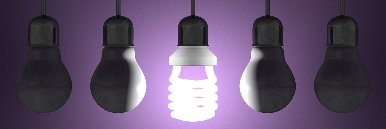 What It's Like to Be a Parent of an Undiagnosed Child Glowing spiral light bulb among tungsten ones in lamp sockets hanging on dark violet textured background