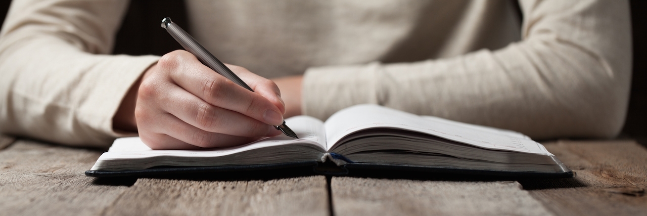 Modest Mouse Song Inspires Woman With Bipolar Disorder hand writes with a pen in a notebook