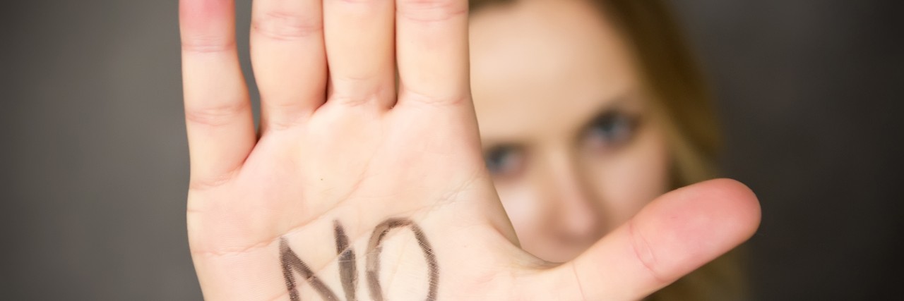 Young woman with the word NO written on her hand.