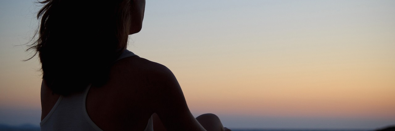 Lonely young woman, watching the sea sunset