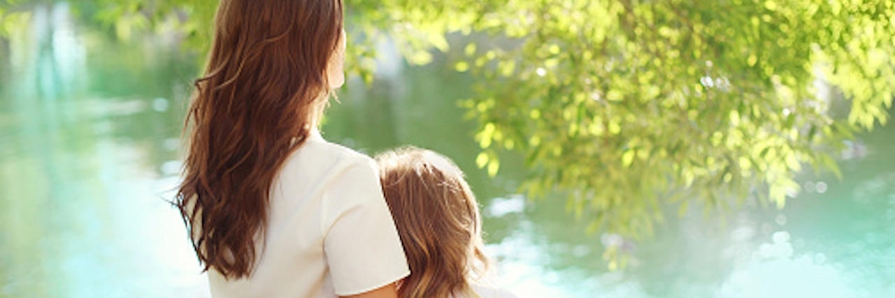 Tips for Parenting a Daughter With ADHD mother and daughter sit together next to a lake