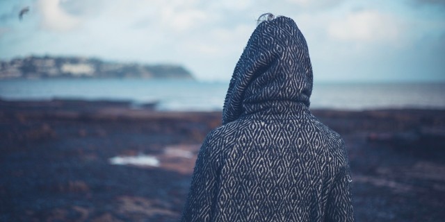 a woman wearing a hoodie looking at water