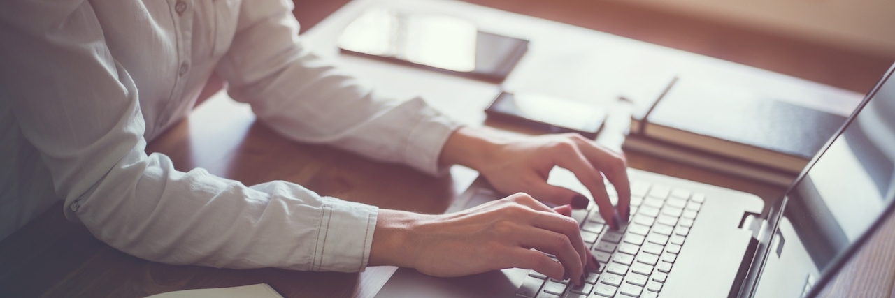 Deciding to Apply for Social Security Disability Insurance Woman working in home office hand on keyboard close up.