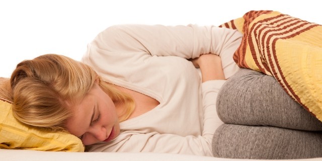 5 Things to Remember in a Myasthenia Gravis Crisis Woman lying in bed holding belly because of the pain in stomach.