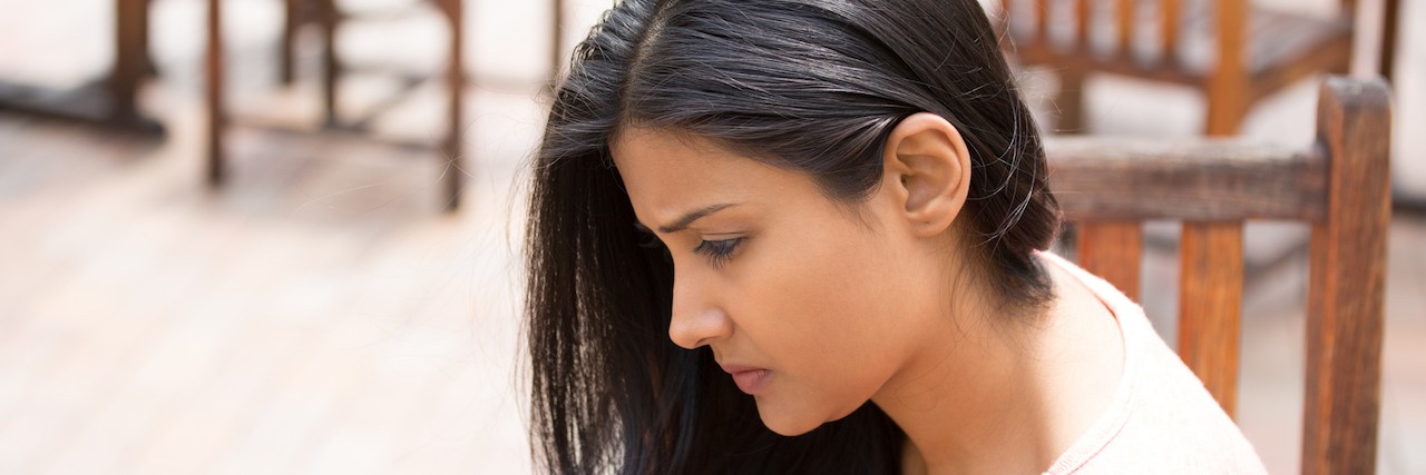 Finding Gratitude ith Chronic Illness Even Life Seems Unfair Closeup portrait, dull upset young woman sitting on bench, really depressed, down about something, isolated outdoors background.