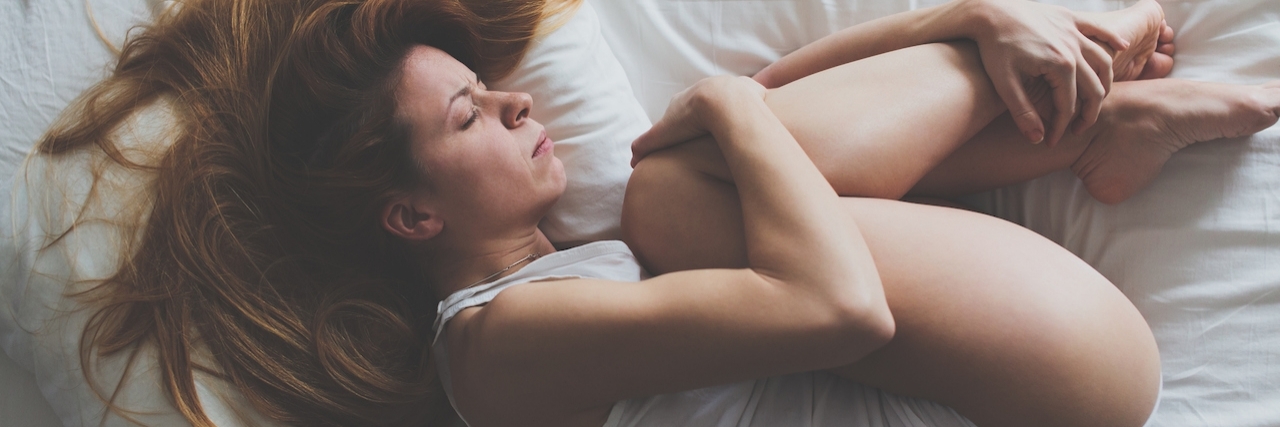 Advice for Living With Ehlers-Danlos Syndrome Young woman lying down on the bed in fetal position