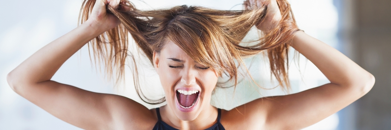 Frustrated young woman screaming and pulling her hair