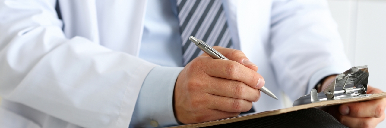 When My New Doctor Was Supportive of My Ehlers-Danlos Syndrome Male medicine doctor hand holding silver pen writing something on clipboard closeup. Ward round, patient visit check, medical calculation and statistics concept. Physician ready to examine patient