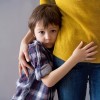 Sad little child, boy, hugging his mother at home,