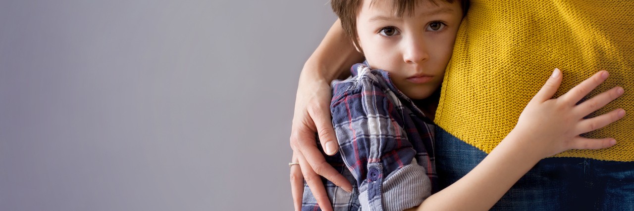 Sad little child, boy, hugging his mother at home,