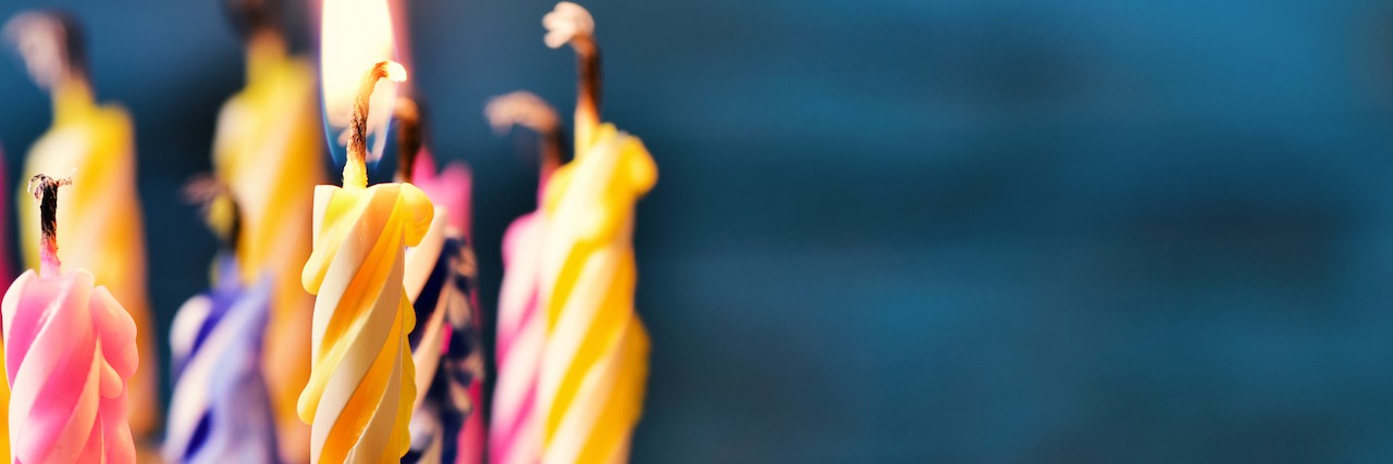 Letter to People Who Don't Like Celebrating Their Birthday closeup of some unlit candles and just one lit candle after blowing out the cake