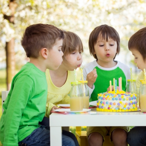 Happy sweet preschool children, friends and relatives, celebrating fifth birthday of cute boy, outdoor in blooming apple tree garden, springtime, late afternoon