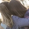 A view from behind of two friends hugging in a park