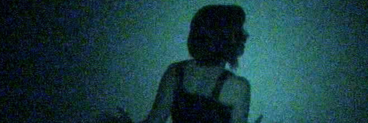 Woman from behind which looks lost in the darkness blue.