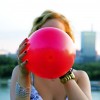 girl holding a red balloon in front of her face