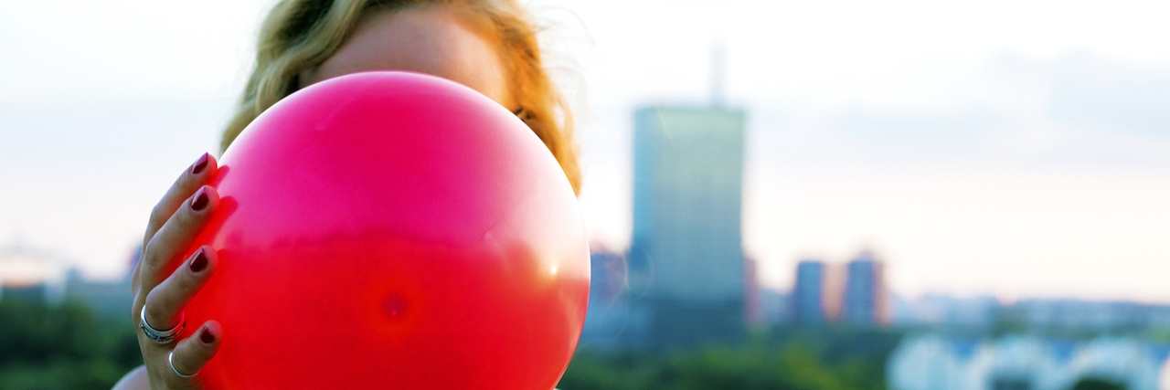 girl holding a red balloon in front of her face