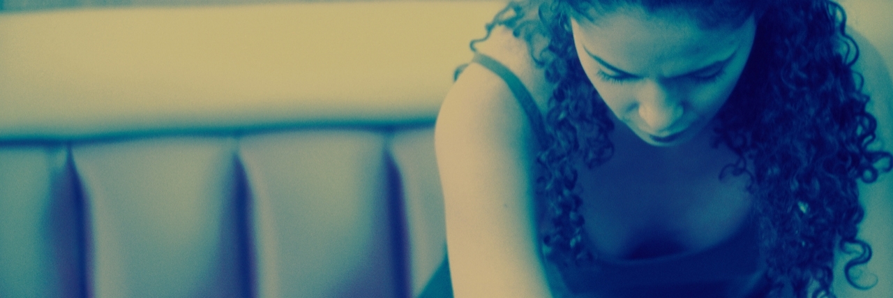 Mental Illness: Crying for Help Without Speaking Young woman sitting on a couch with her head down