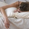Woman lying in bed with face buried in pillow