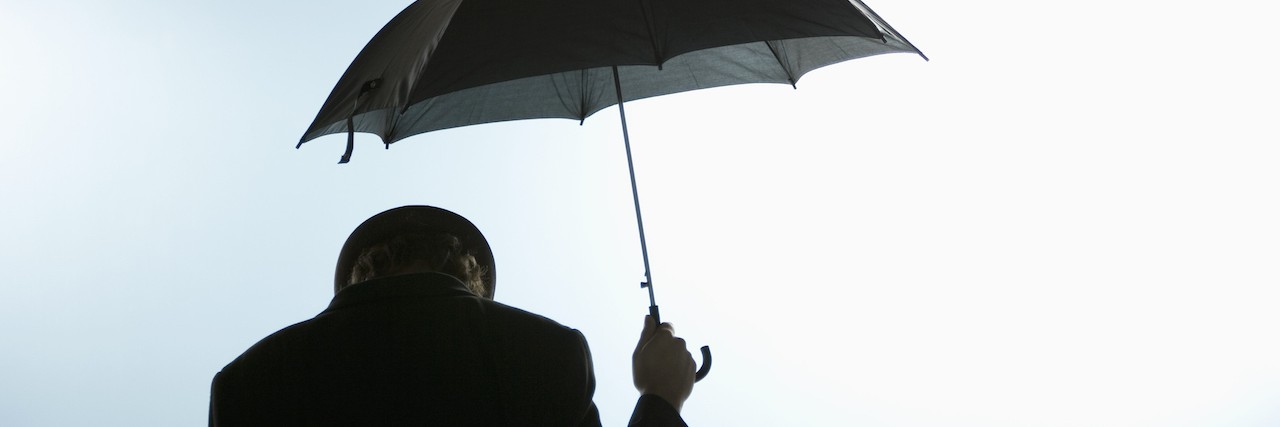 What It Means to Have 'Getting-by' Depression Person with head down holding umbrella