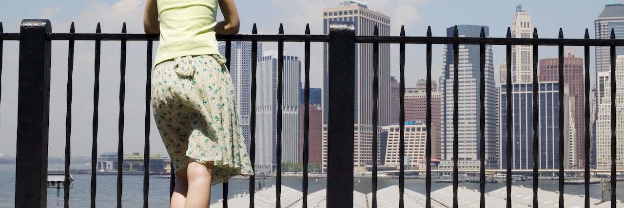 Woman leaning on railing in New York City looking at the skyline
