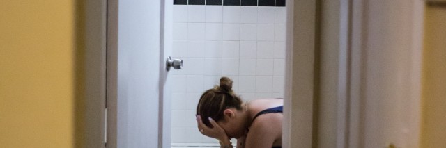 Alix sitting in her bathroom with her head in her hands