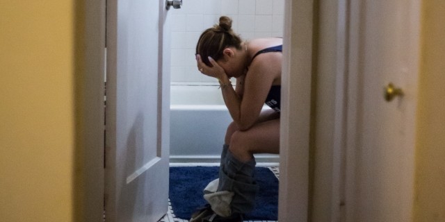 Alix sitting in her bathroom with her head in her hands