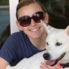 woman wearing sunglasses with white dog on her lap