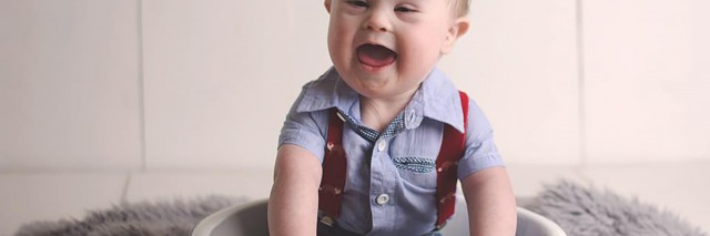 Meagan's son. Toddler with Down syndrome sitting in a bowl and laughing.