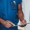 Group of doctors standing consulting patient records on a tablet computer, close up view