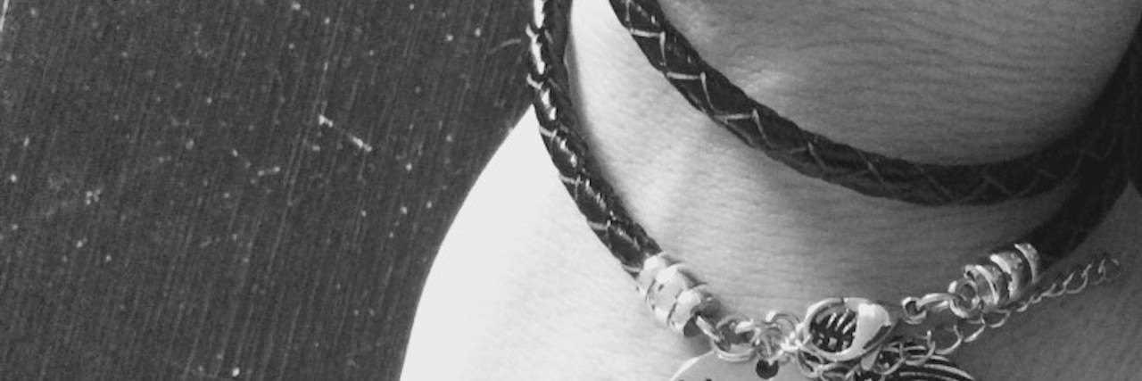 Close up of a bracelet that reads: With brave wings she flies