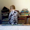 Toddler boy playing in front of books and toys