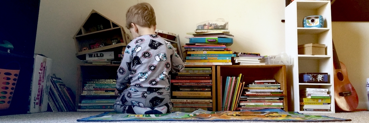 Toddler boy playing in front of books and toys