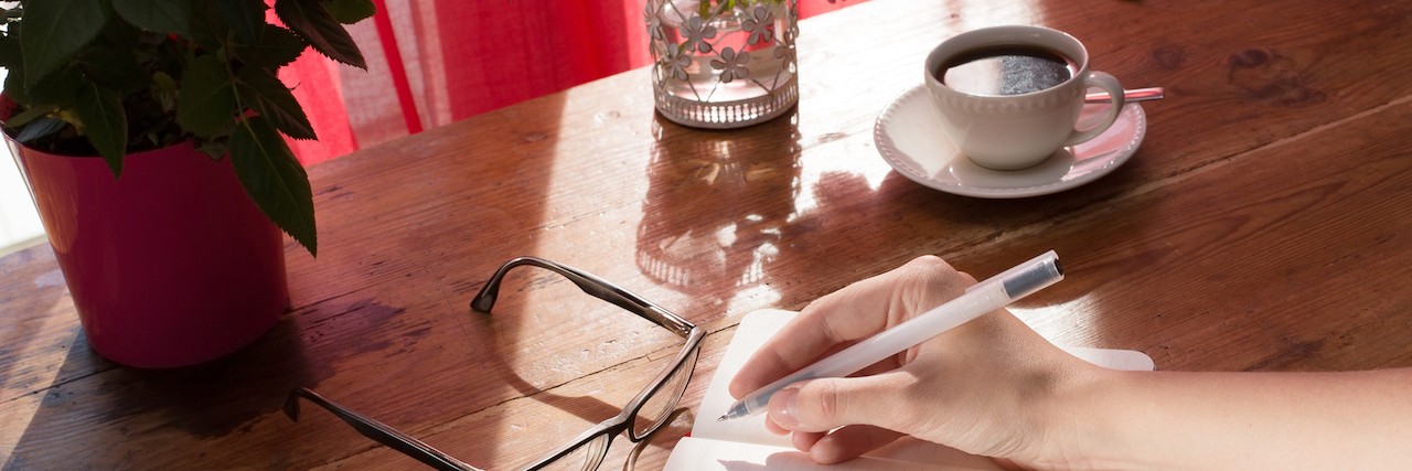 What Future Partner Needs to Know About Chronic Fatigue Syndrome female writing a note in a vintage notebook next to red flowers
