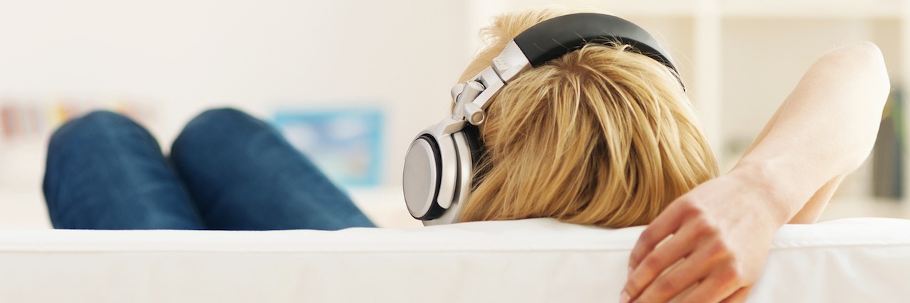 Songs for Dealing With Being Chronically Sick woman sitting on couch with headphones on