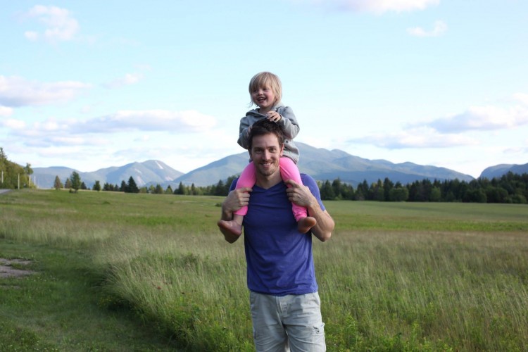 dad with his daughter on his shoulders in field