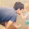 girl and dad putting heads together at the beach