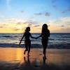 Two women walk together on the beach.
